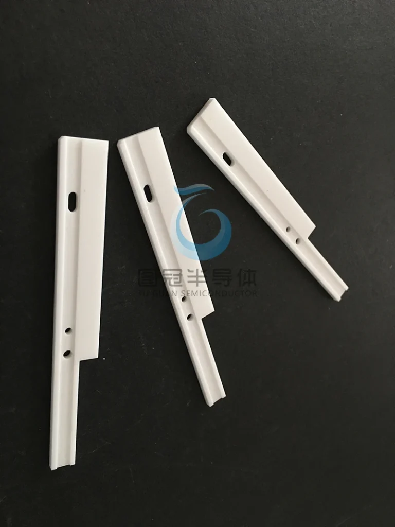 Three precision ceramic inserts or guides with mounting holes and stepped profiles.
