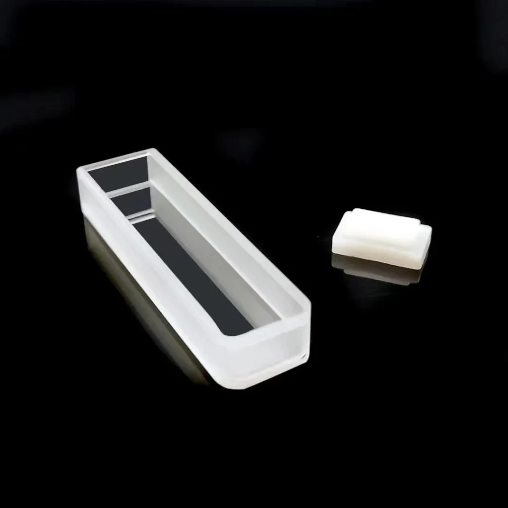 Top-down view of a clear Fused Quartz rectangular cuvette showing its open top and internal structure, with a white stopper nearby.