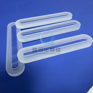Three clear, elongated Fused Quartz sight glasses with frosted edges and rounded ends, lying on a blue surface.