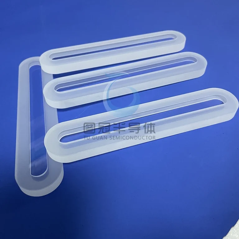 Three clear, elongated Fused Quartz sight glasses with frosted edges and rounded ends, lying on a blue surface.